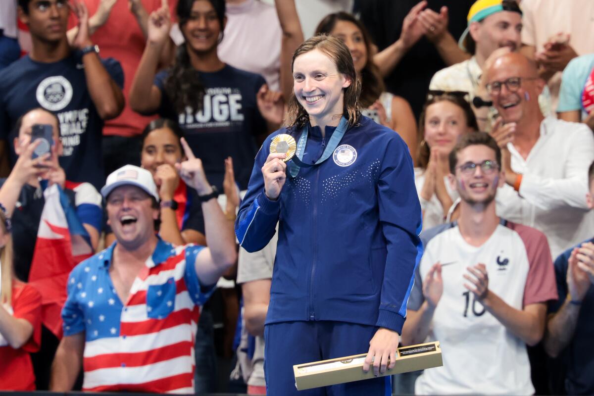 Katie Ledecky holds up her gold medal after winning the women's 1500-meter swimming final 