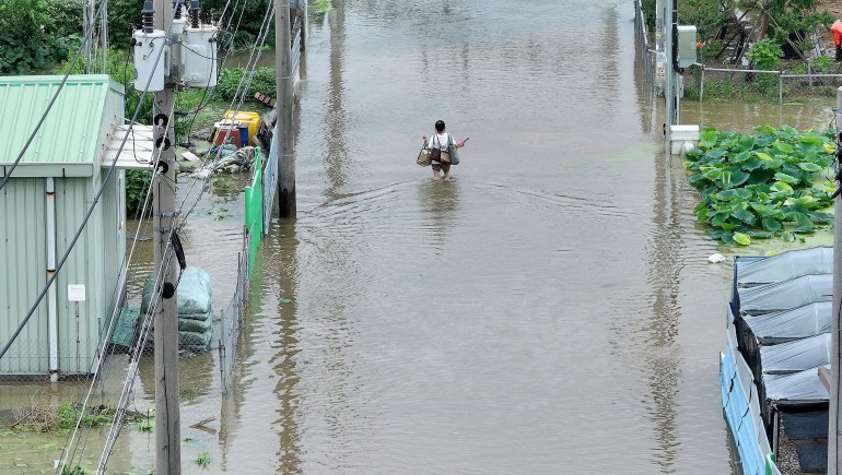 A woman carrying belongings makes her way through a flooded street 