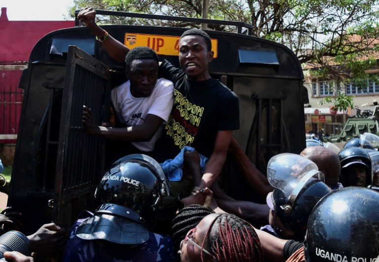 Ugandan police officers detain protestors during a rally against what the protesters say are rampant corruption and human rights abuses by the country's rulers in Kampala, Uganda