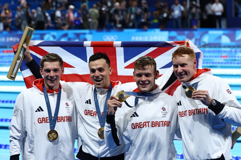 Paris 2024 Olympics - Swimming - Men's 4x200m Free Relay Victory Ceremony - Paris La Defense Arena, Nanterre, France - July 30, 2024. Gold medallists James Guy of Britain, Tom Dean of Britain, Matthew Richards of Britain and Duncan Scott of Britain celebrate on the podium. REUTERS/Evgenia Novozhenina