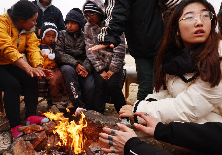 Migrants from China and Ecuador huddle together around a fire at a makeshift camp after crossing the border into the US.