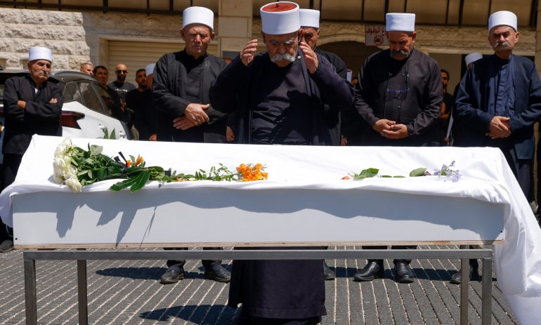 Elders and mourners pray by the coffin of Guevara Ibrahim, 11, killed in a reported strike from Lebanon two days earlier, during his funeral in the Druze town of Majdal Shams in the Israeli-annexed Golan