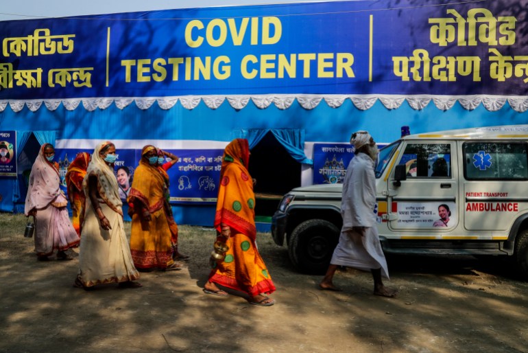 A group of Hindu pilgrim headed for the Gangasagar pilgrimage walk past a temporary COVID-19 testing camp at a transit camp in Kolkata, India, Sunday, Jan. 10, 2021. This year due to the pandemic, authorities are anticipating less number of pilgrims during the annual pilgrimage that coincides with the Makar Sankranti festival that falls on Jan. 14. (AP Photo/Bikas Das)