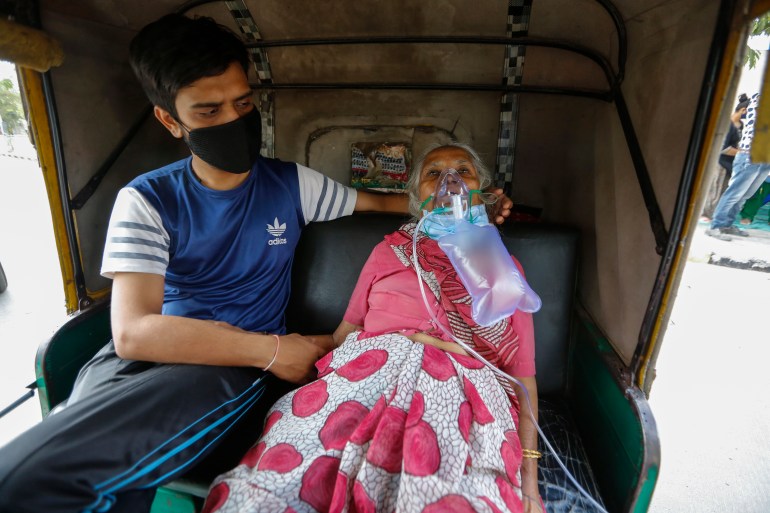 A COVID-19 patient wearing oxygen mask waits inside an auto ricksha to be attended and admitted to a dedicated COVID-19 government hospital in Ahmedabad, India, Saturday, April 17, 2021. The global death toll from the coronavirus topped a staggering 3 million people Saturday amid repeated setbacks in the worldwide vaccination campaign and a deepening crisis in places such as Brazil, India and France. (AP Photo/Ajit Solanki)