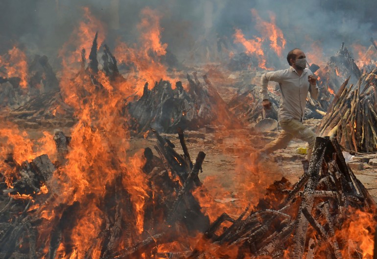 A man runs to escape the heat from multiple funeral pyres of COVID-19 victims at a crematorium on the outskirts of New Delhi, India, on April 29, 2021. (AP Photo/Amit Sharma)