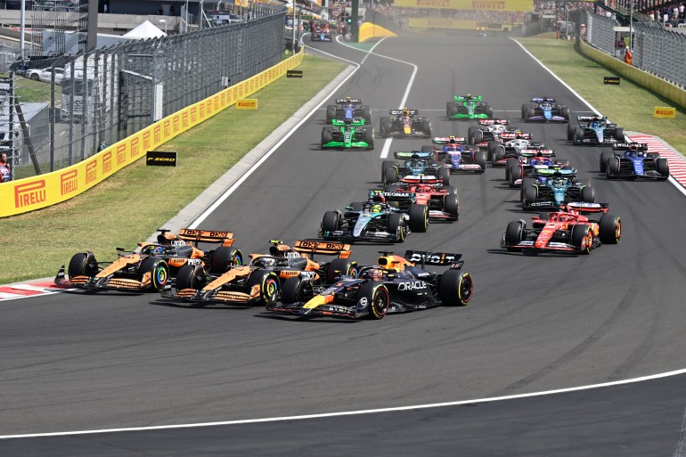 Three F1 drivers go around corner at same time during race.