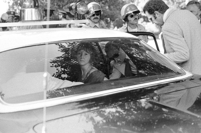 FILE- In this Sept. 5, 1975 file photo, a U.S. Secret Service agent and a uniformed police officer escort and put Lynette "Squeaky" Fromme into a police car in Sacramento, Calif., after pointed at President Gerald Ford. Almost 38 years after the assassination attempt, a federal judge has allowed the release of a videotaped testimony given by Ford, that was later used in Fromme's trial. Fromme, a devoted follower of the infamous Charles Manson, wearing a red robe, stepped out from behind a tree and pointed a loaded pistol at the President. (AP Photo/File)