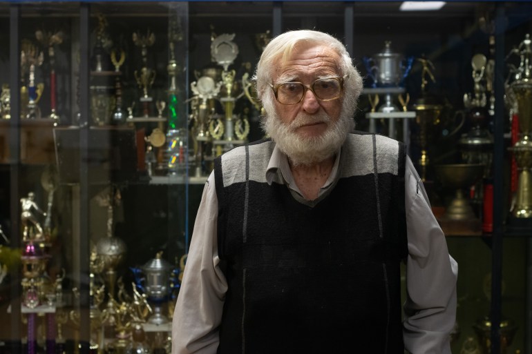 Jorge Zisman stands in front of the trophy case at the sports club Franja de Oro.