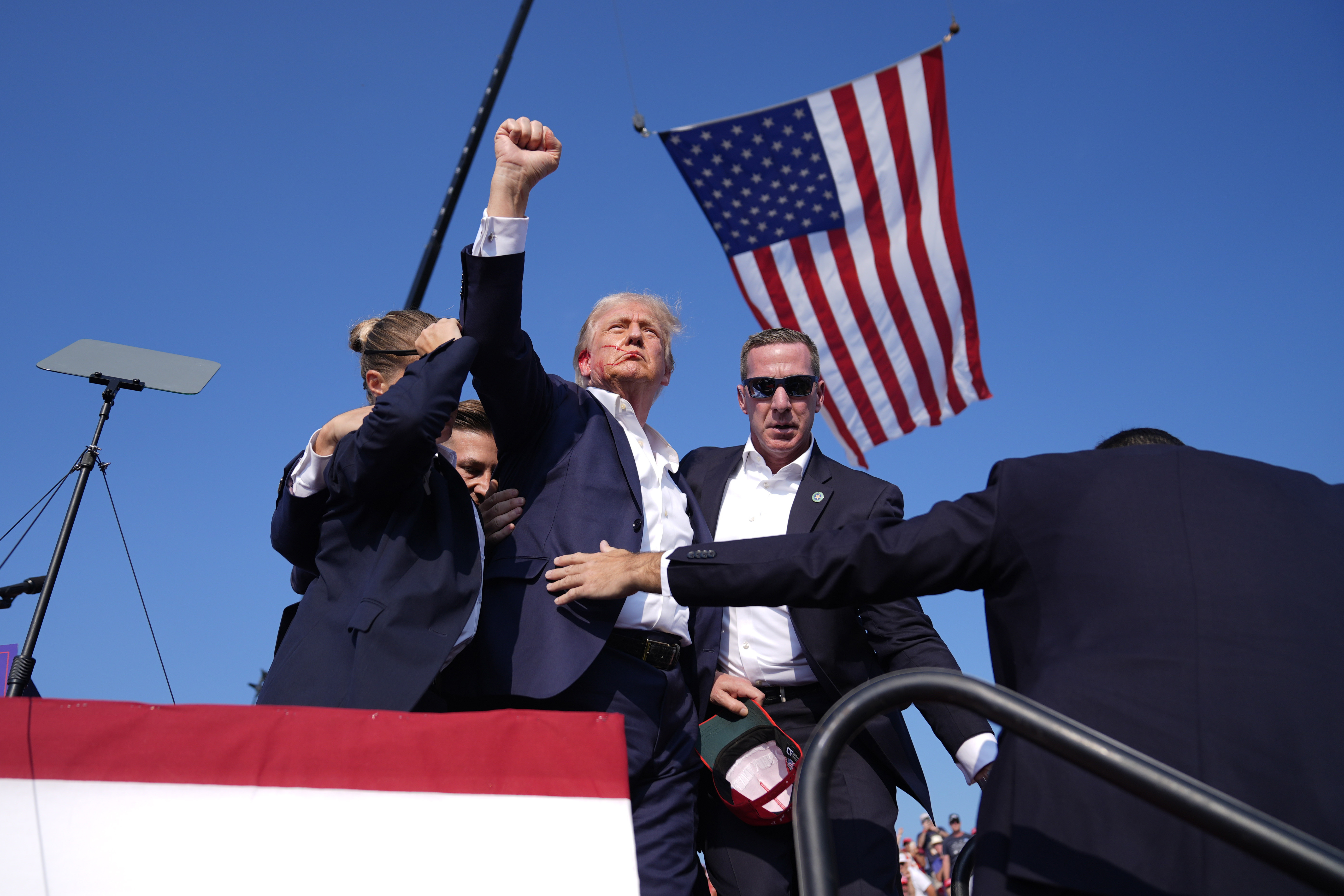 Donald Trump gestures as he is surrounded by U.S. Secret Service agents after being shot in the ear at a rally over the weekend