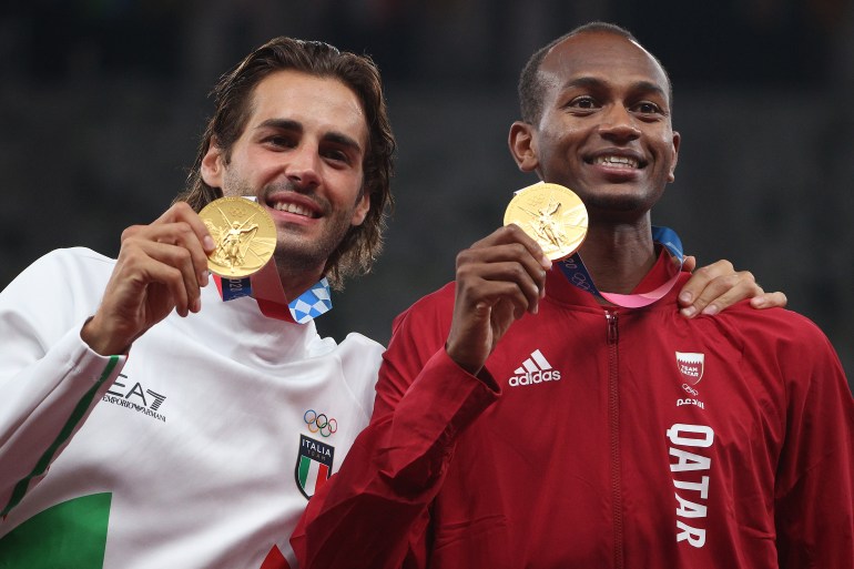 Athletes hold gold medal.