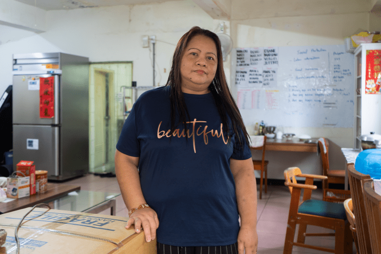 Liezel Bartolome. She is standing in an office. She is wearing a black T-short with the word 'Beautiful' written on the front. She has long black hair