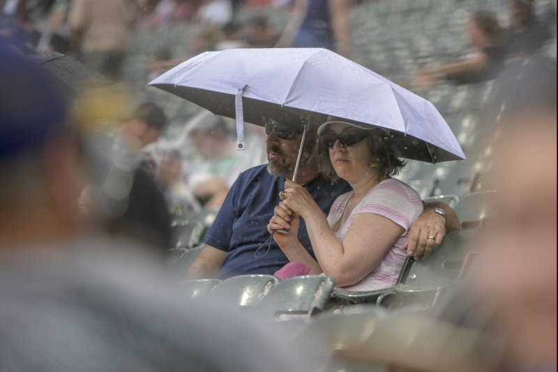 Fans huddle under an umbrella as the rain starts to fall during the eighth inning of a game between the Chicago White Sox and Seattle Mariners at Guaranteed Rate Field in Chicago, IL on Sunday. The Mariners won 6-3. Photo by Mark Black/UPI