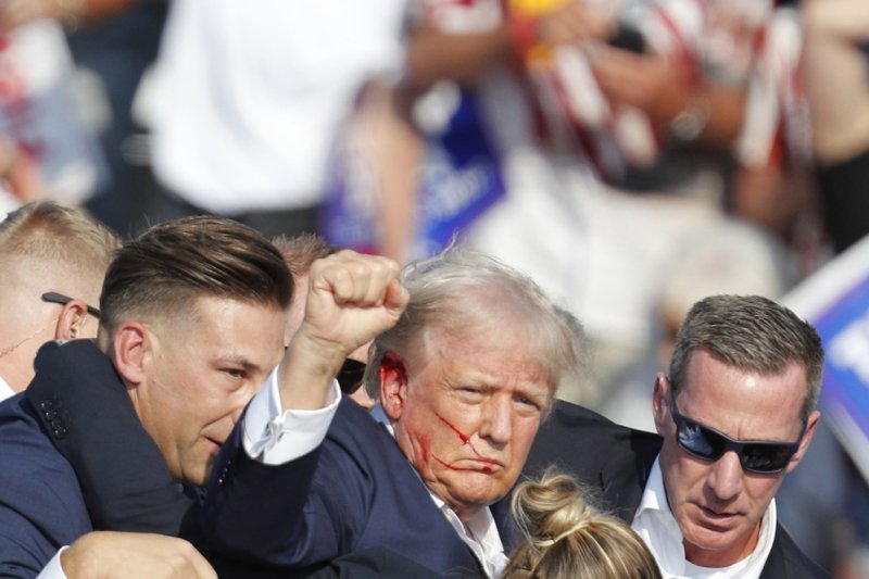 Before secret service agents rushed him off stage, Donald Trump pumped his fist at the crowd while bleeding from his right ear. Photo by David Maxwell/EPA-EFE