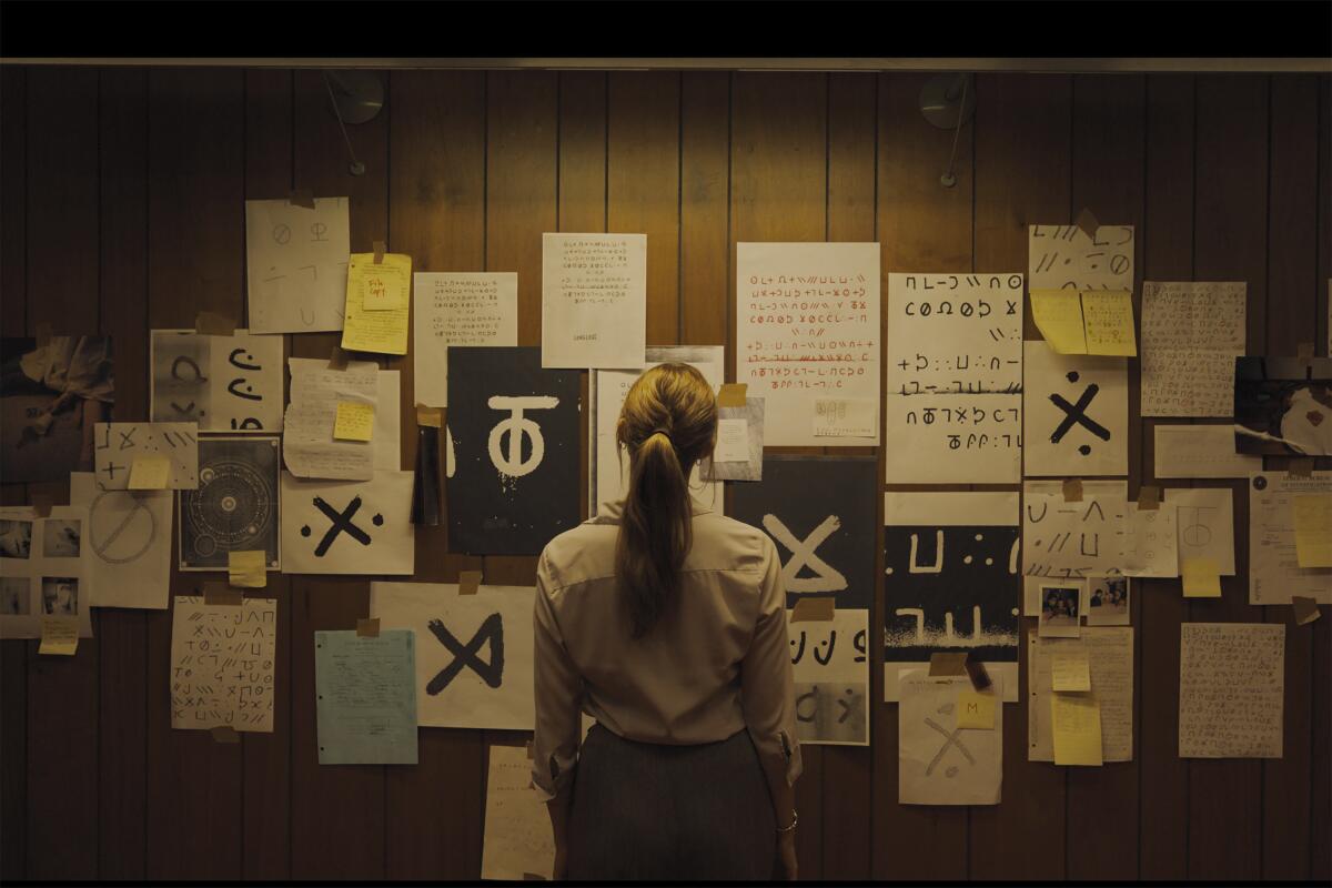 An FBI agent studies a wall of clues.