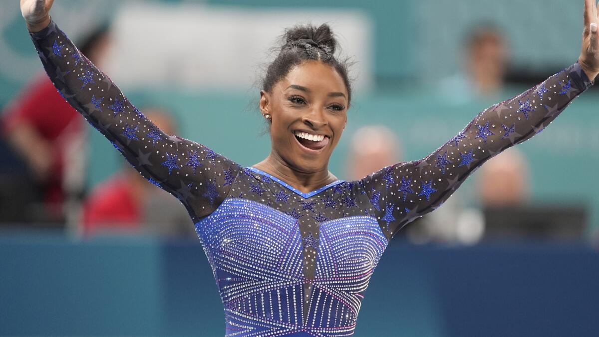 Simone Biles smiling after performing on the balance beam during the women's all-around individual finals 