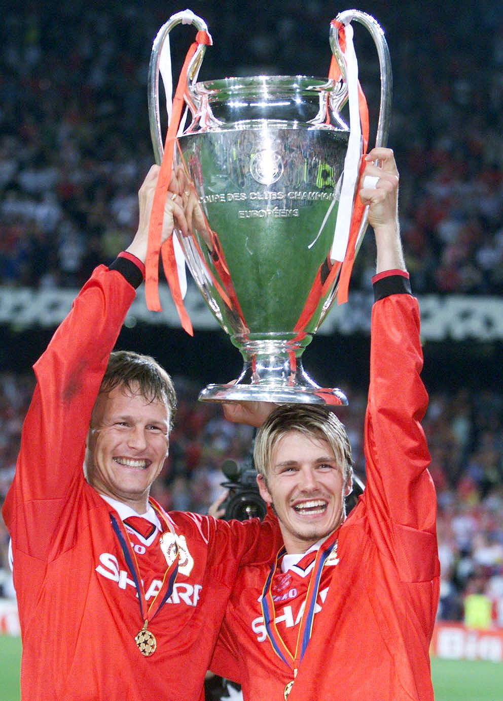 Teddy Sheringham and David Beckham lift the UEFA Champions League trophy after beating Bayern Munich in May 1999