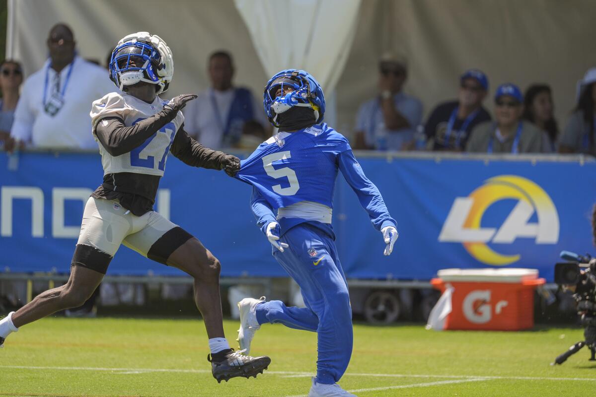 Rams cornerback Tre'Davious White (27) tries to hold wide receiver Tutu Atwell (5) as they pursue a pass during camp.