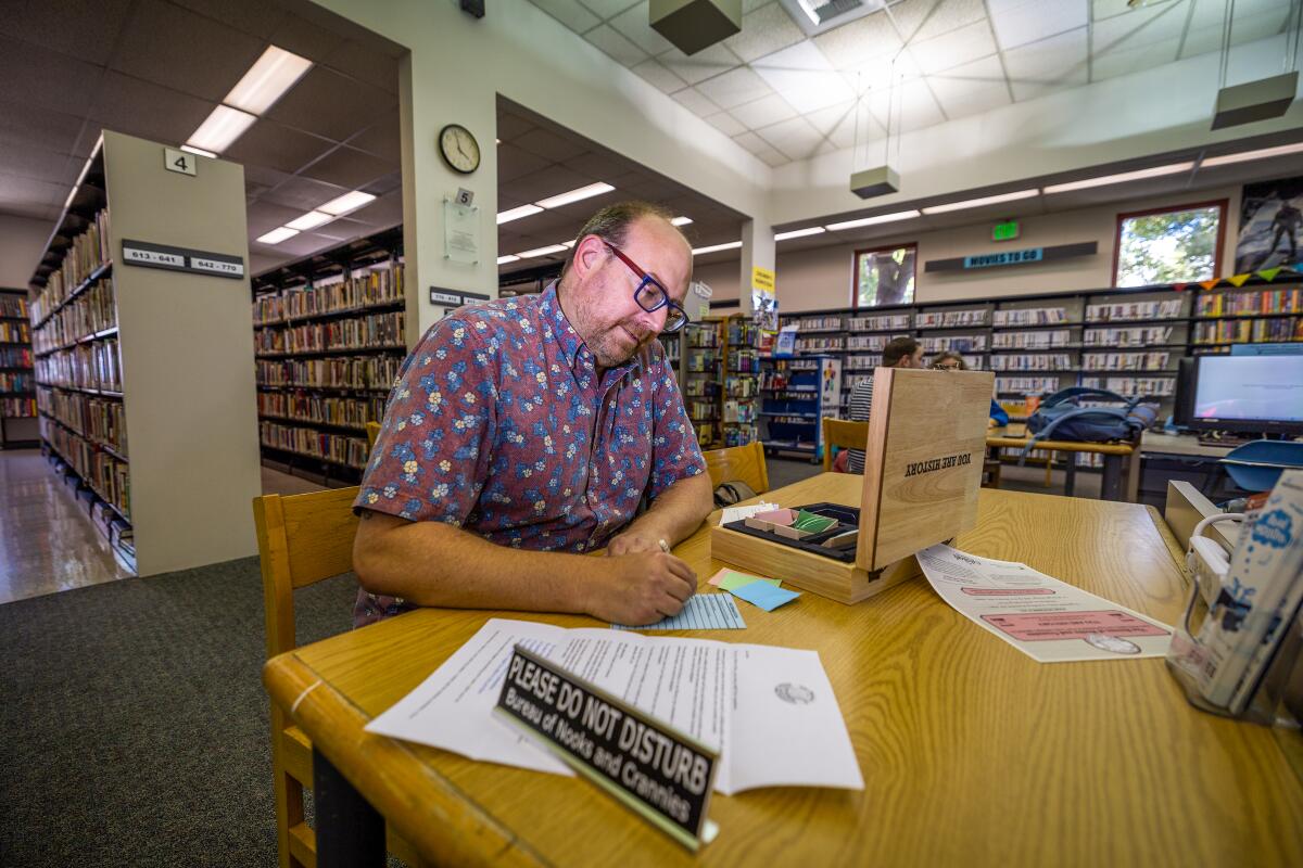 A man sitting at a table, writing on notecards, as part of the immersive puzzle experience.