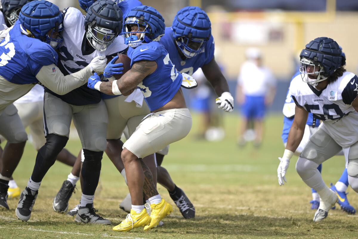 The Rams'  Kyren Williams (23) tries to push through a group of Cowboys defenders during their joint practice in Oxnard.