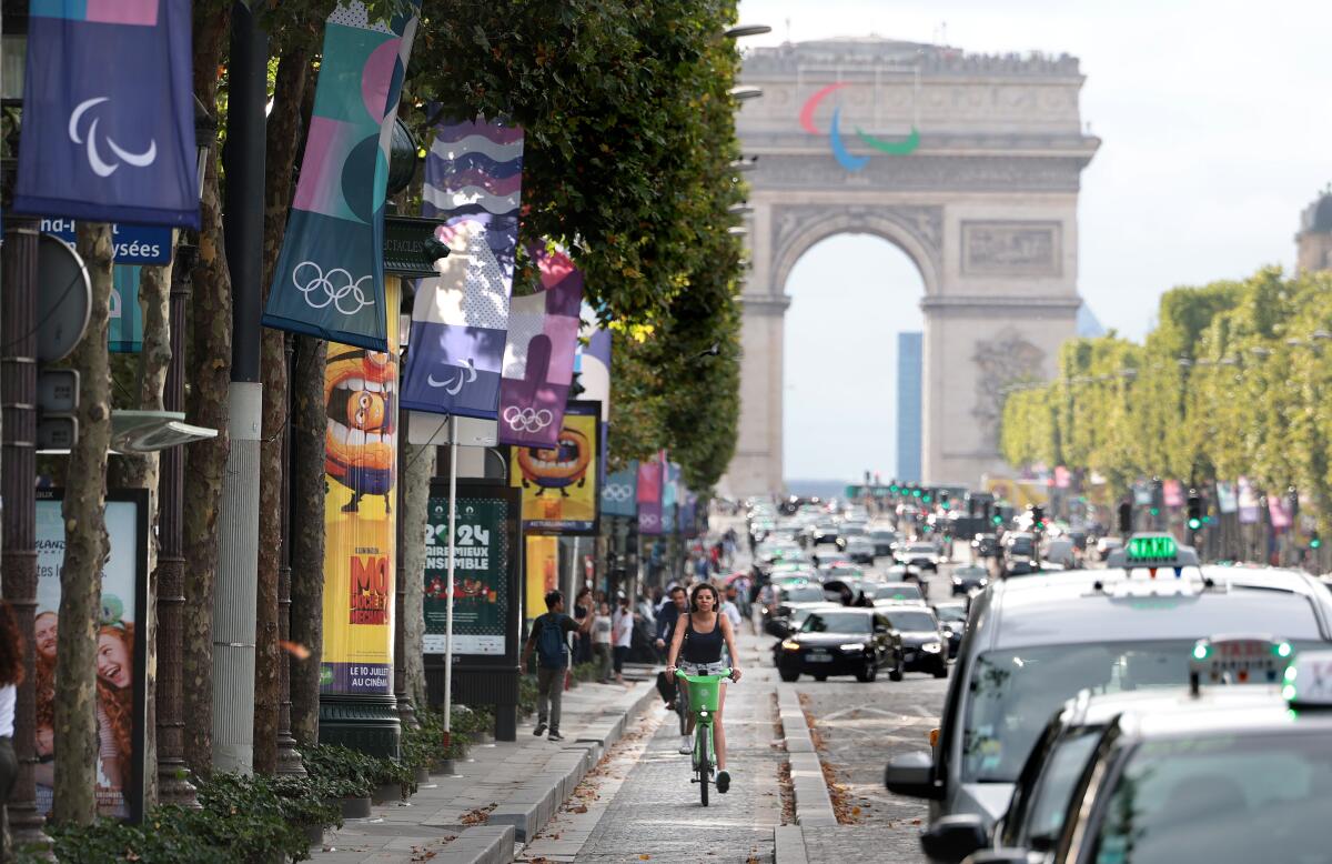 A woman rides a bicycle along the Champ-Elysees before the Olympics in Paris on July 23.