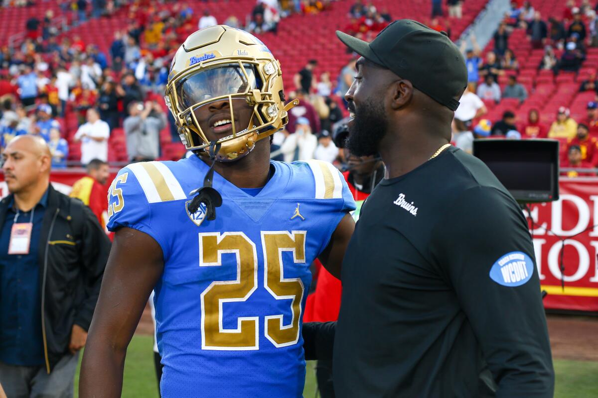 UCLA Bruins running back TJ Harden gets a hug from coach DeShaun Foster.