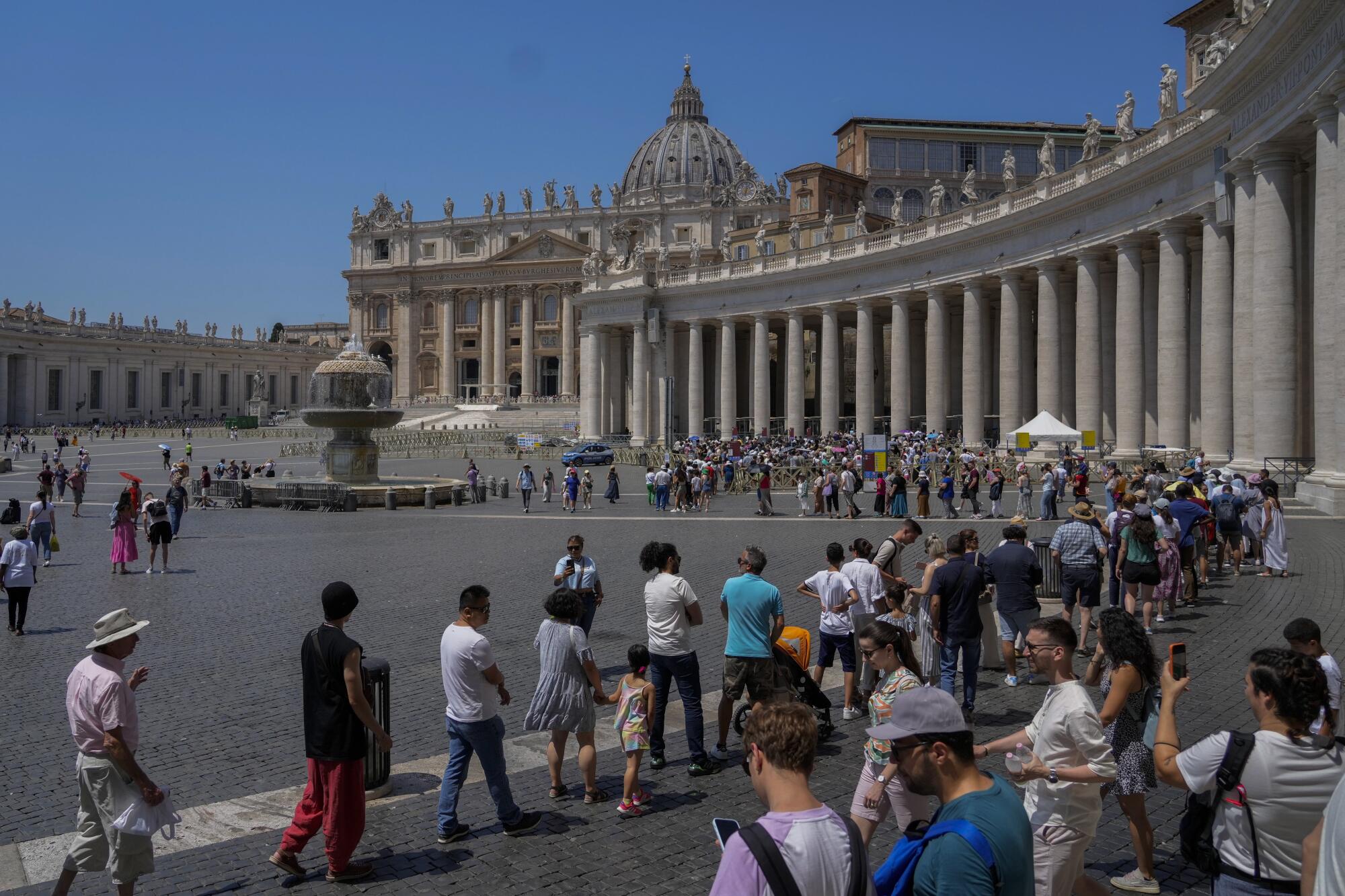 Scores of people standing in a long line as others walk around St. Peter's Square in Vatican City