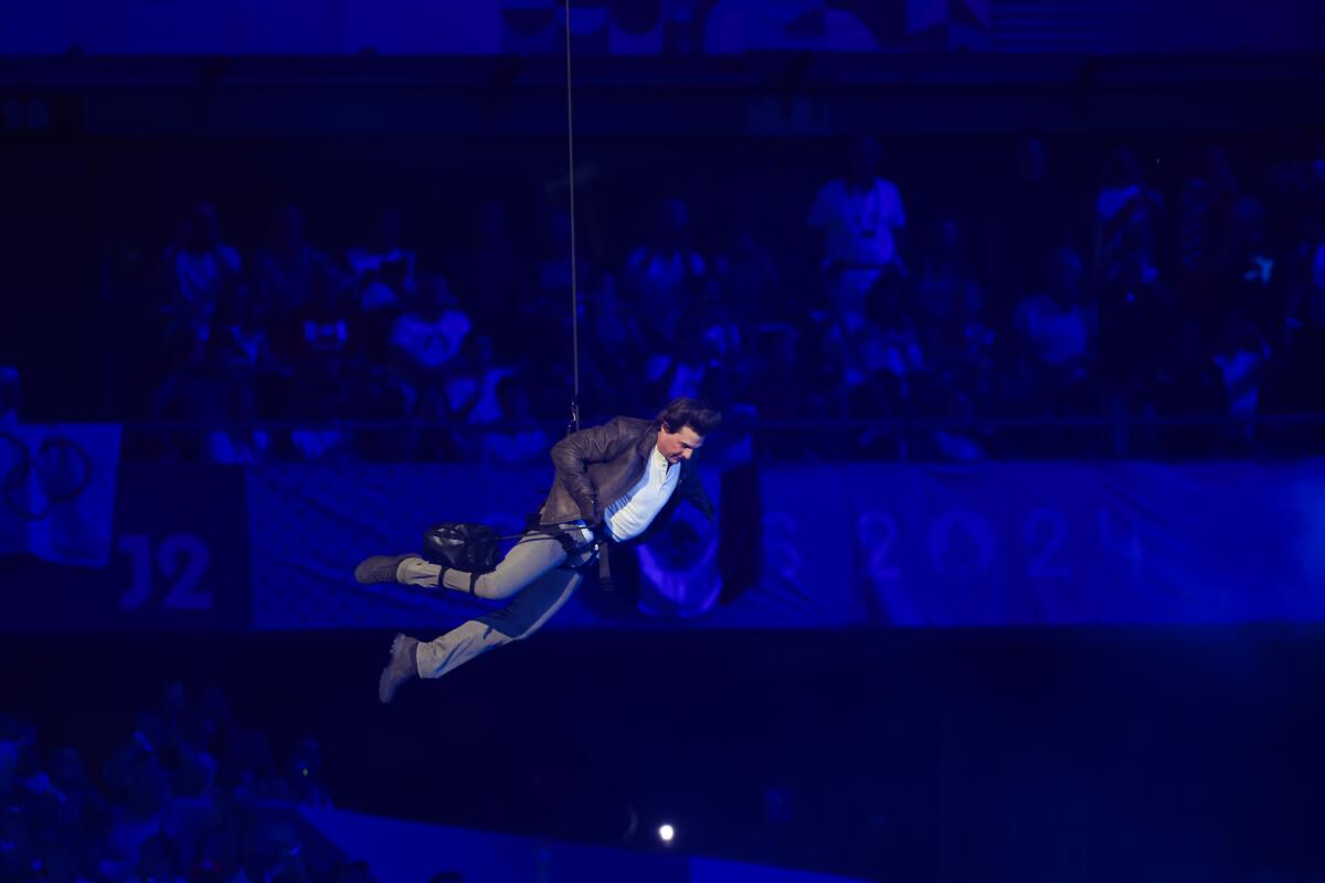 Tom Cruise rappels from the top of a stadium during the closing ceremony of the Olympics.