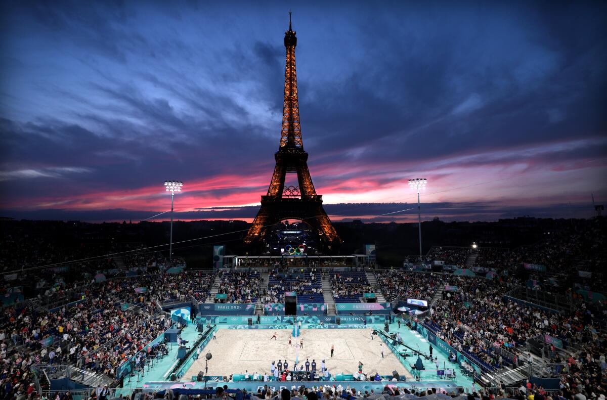 The sun sets over the Eiffel Tower as the U.S. plays Canada in Olympic women's beach volleyball.