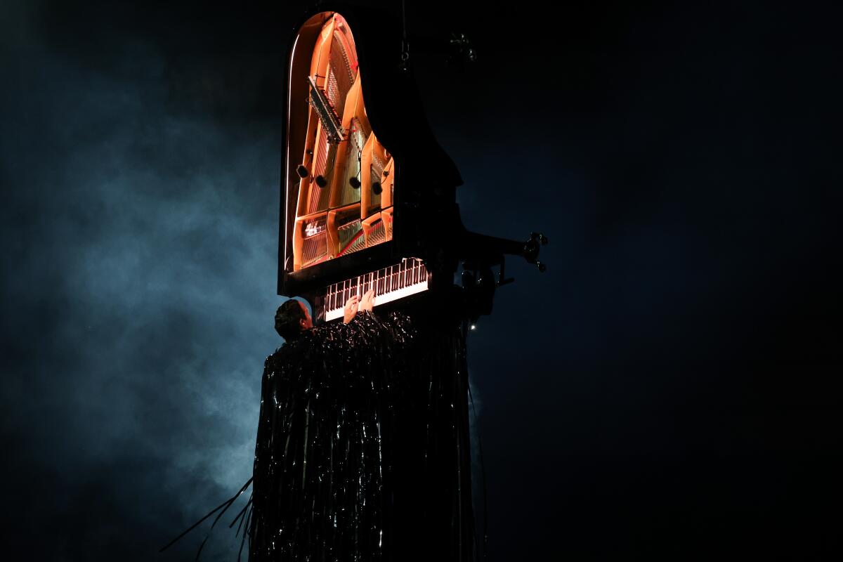 Alain Roche plays a piano hanging vertically during the closing ceremony.