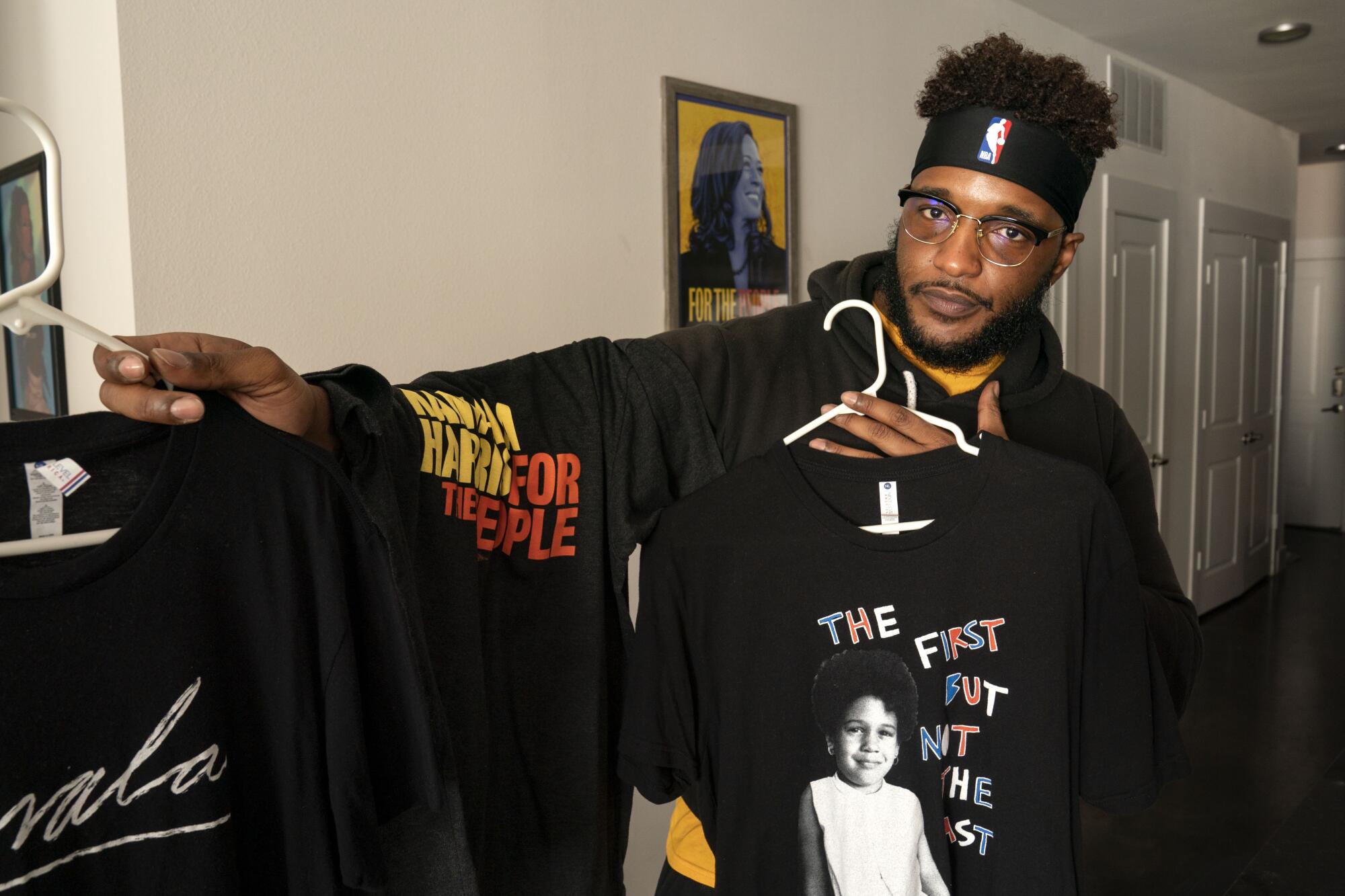 A man holds T-shirts with Kamala Harris logos.