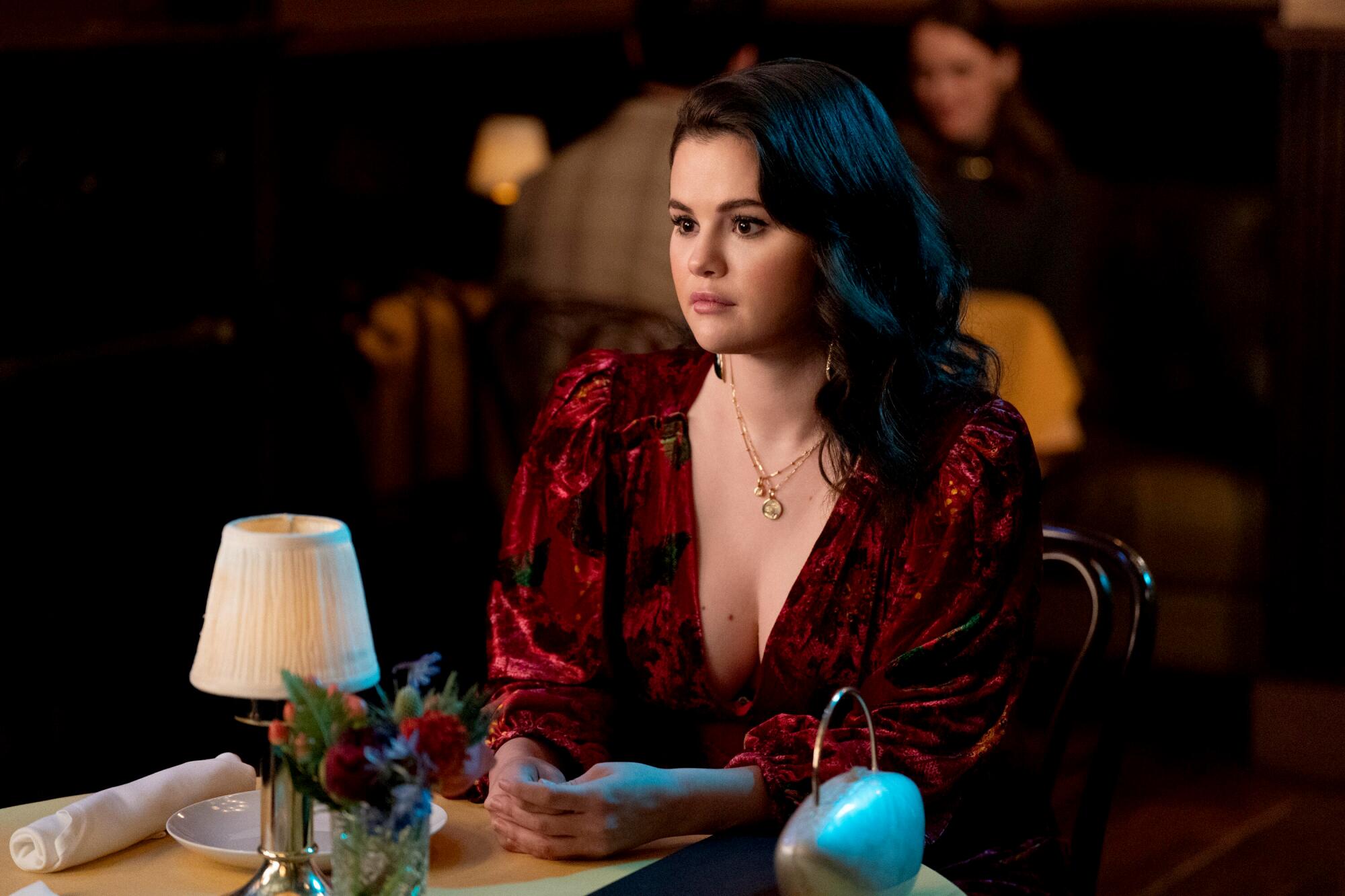 A young woman sits at a restaurant table in "Only Murders in the Building."