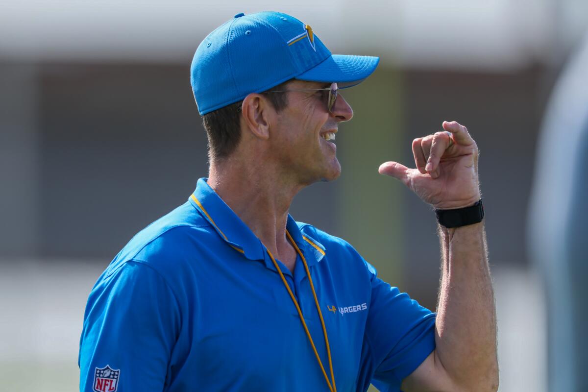 Chargers coach Jim Harbaugh signals his team during camp practice.