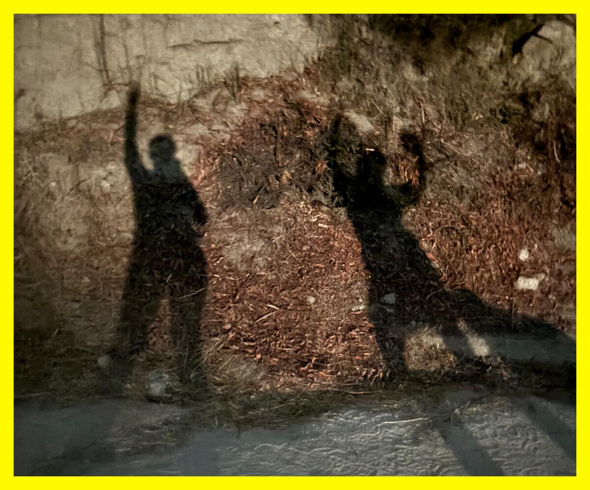 Two human silhouettes against a rocky wall.