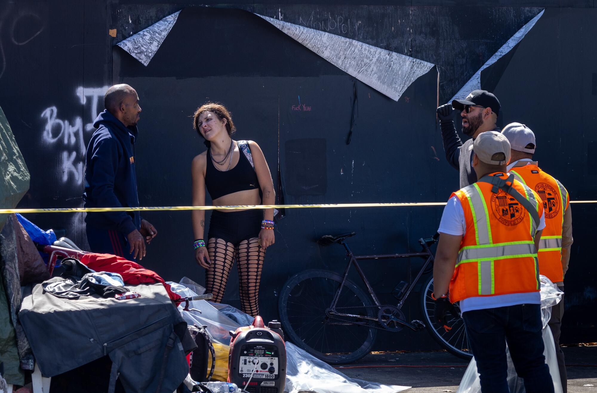 A homeless couple, left, talks with workers from Mayor Karen Bass' Inside Safe program at a homeless encampment in Hollywood.