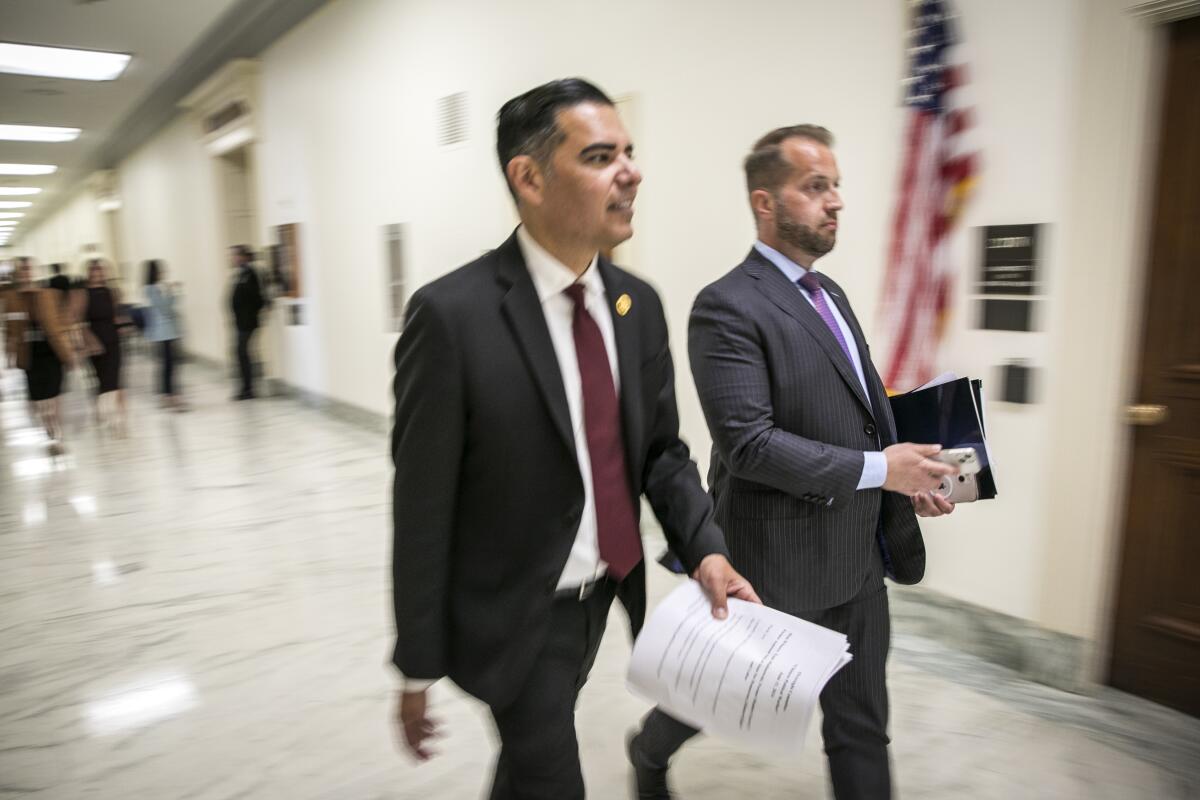 Rep. Robert Garcia, left, and his chief of staff, Robert Edmonson, walk down a hall.