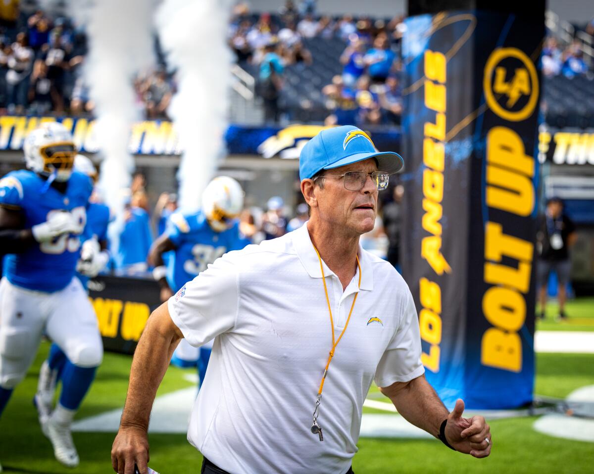 Chargers coach Jim Harbaugh leads his players onto the field before Saturday's preseason game against the Rams.