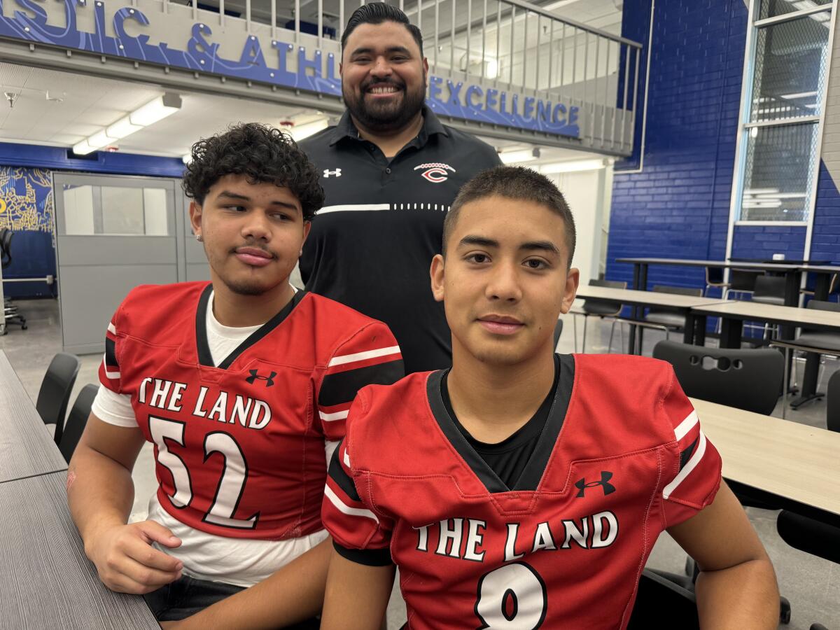 First-year Cleveland coach Mario Guzman with lineman Joshua Reyes (left) and quarterback Domenik Fuentes.