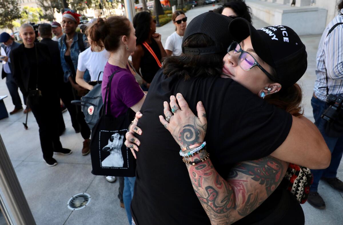 Anita Joy, right, who was with Johnny Factor when he was shot, hugs Gary Hoiness following news conference.