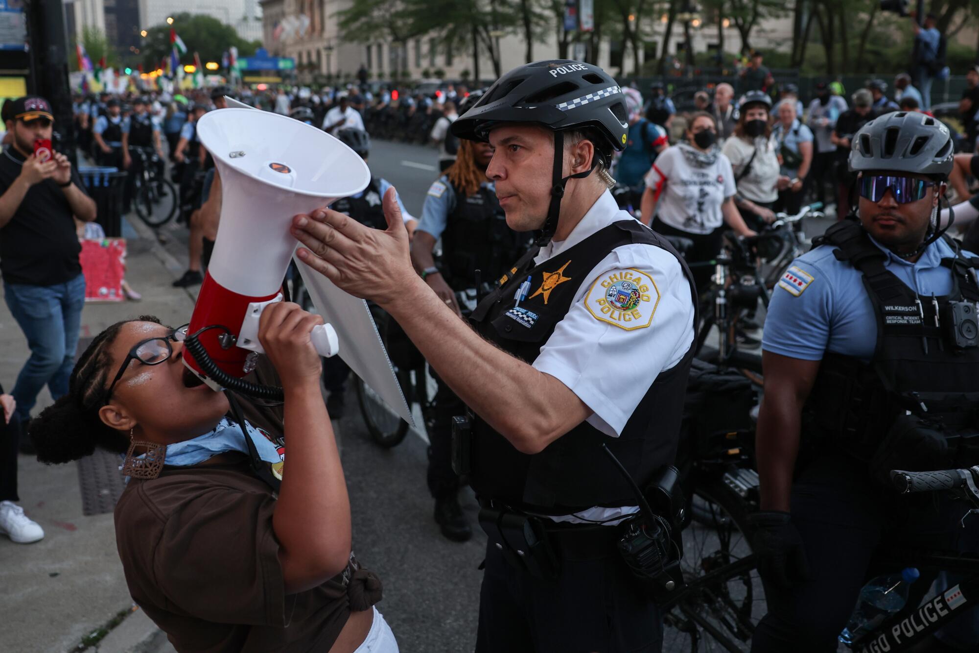 A law enforcement officer tilts a protester's megaphone away from himself.