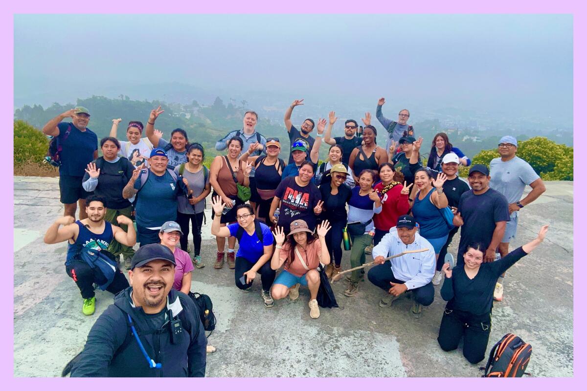 The 5 AM Crew poses at the top of a mountain. Morning fog is seen in the distance.