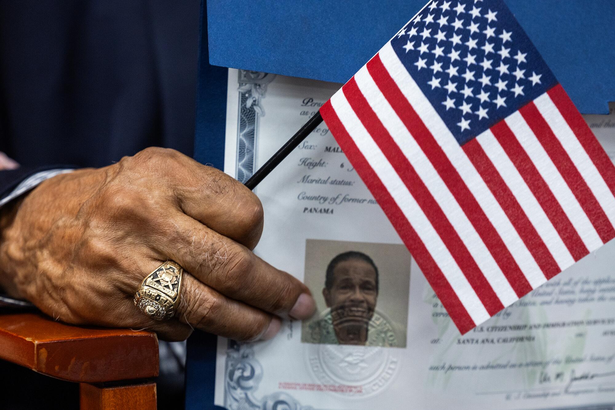 With his Baseball Hall of Fame ring on, Rod Carew holds an American flag and his certificate of naturalization.