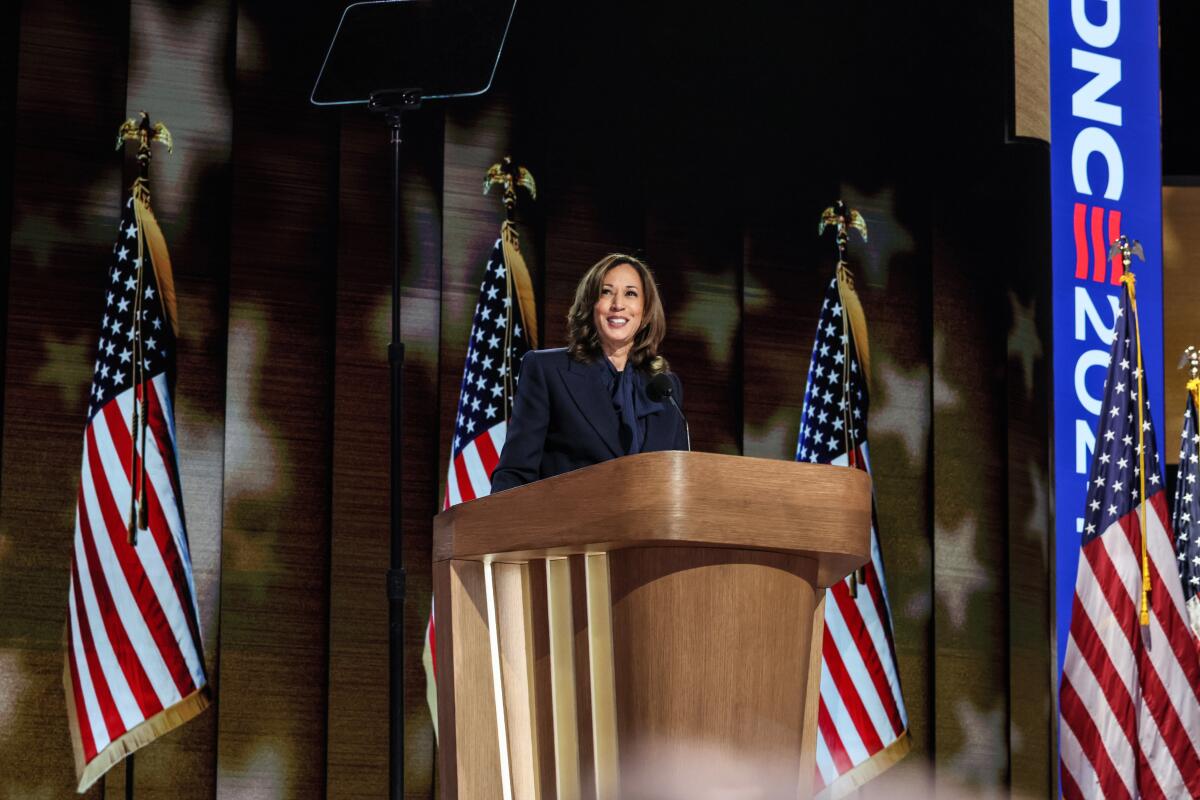 Kamala Harris at a lectern with American flags behind her.