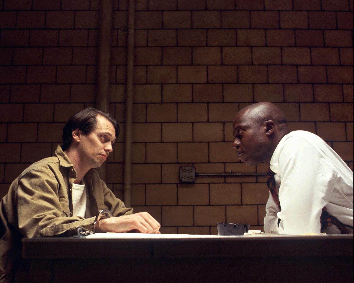 Two men sit at a table in a scene from "Homicide: Life on the Street." 