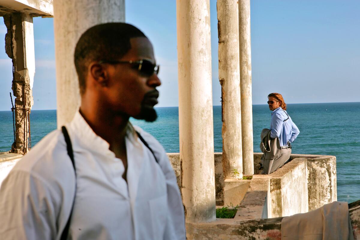 Two men in white stand far apart, with the ocean as their backdrop, in a scene from the 2006 movie "Miami Vice."