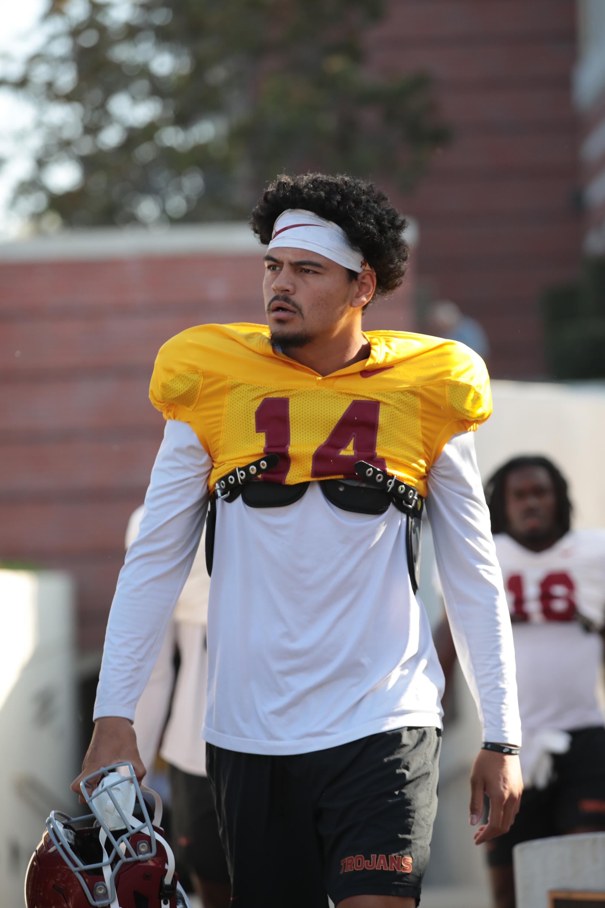 USC quarterback Jayden Maiava walks with his helmet off across the practice field.