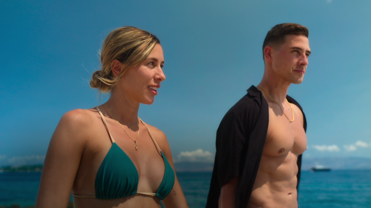 An engaged couple in swimwear on a sunny beach.