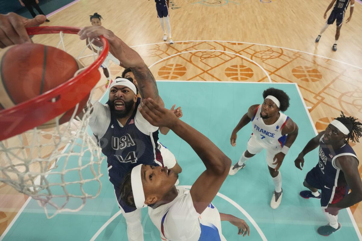 American Anthony Davis dunks over France's Bilal Coulibaly during the gold-medal game at the Paris Olympics.