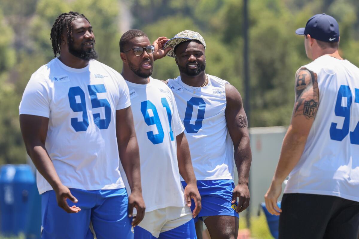 Rams Bobby Brown III (95), Kobie Turner (91), Byron Young (0), and Michael Hoecht (97) talk on the practice field.