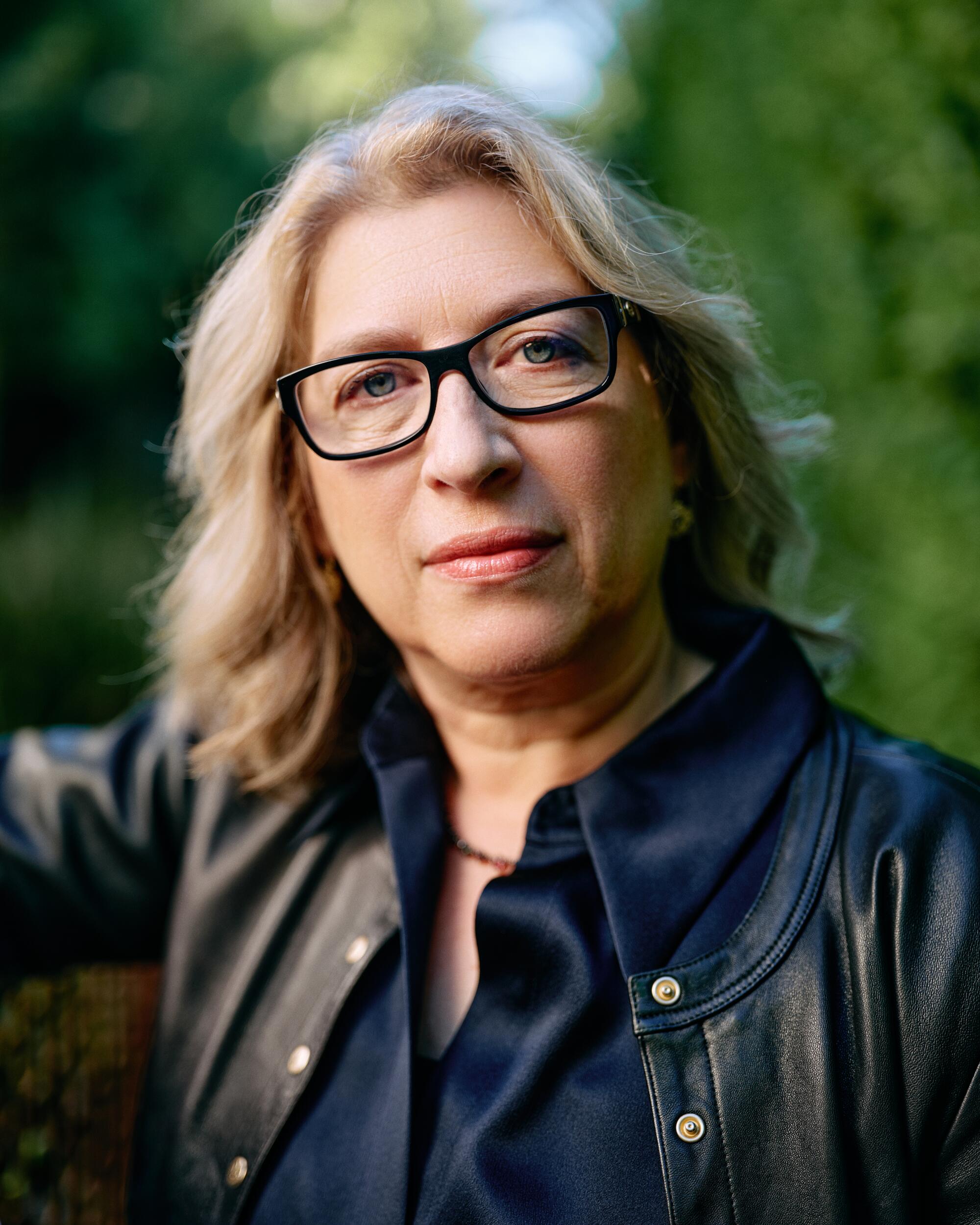 A portrait of a blond woman with glasses.