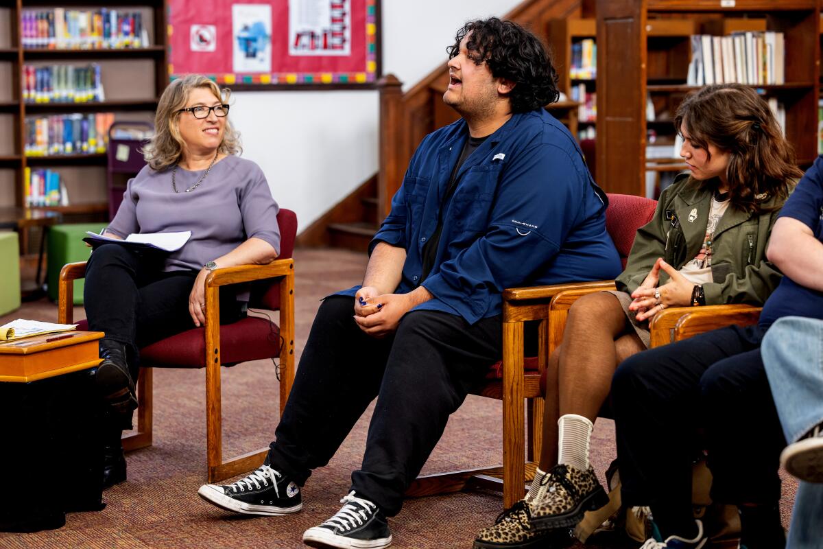 A teen boy in a blue shirt speaking to a group.